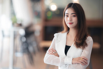 Portrait of female office worker smiling and looking into camera while standing in office room.