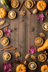 Top down view of various pumpkin pie tarts and fall decorations with copy space in the middle.