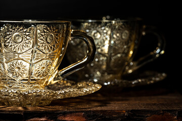 Glass tea cups with a saucer with a pattern on a dark background. Close-up