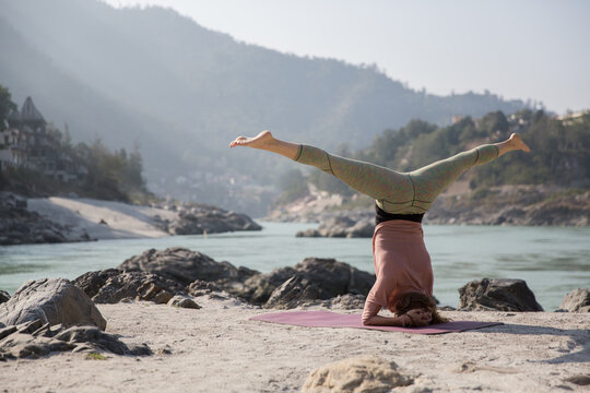 Woman doing headstand next to the river