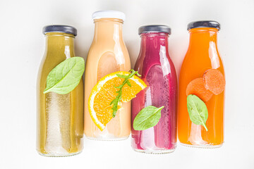 Fruit and vegetable smoothie concept. Portioned bottles with fruit and vegetable smoothies flatlay with fresh ingredients on white table background