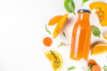 Orange healthy smoothie bottles with ingredients. Vegetable smoothie or juice with  carrot, pumpkin, oranges, white table background, flatlay copy space