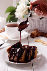 The girl pours chocolate on a freshly baked cupcake. Homemade cakes, cupcakes, and pie. Home cooking at home on self-isolation.