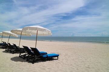 Bed beach and white umbrella on tropical beach with blue sky in the summer morning. Nature and travel concept.