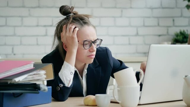 Tired and exhausted woman works late with a pile of documents. Portrait of a workaholic.