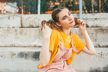 Portrait of a young, blonde girl with pigtails. Strong make up