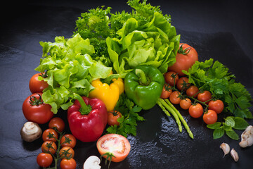 Set of fresh vegetables on black stone background. red yellow and green pepper, tomato, green oak, cos, Romaine, garlic, asparagus, mushroom and coriander with copy space.