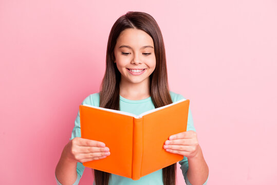 Photo of lovely cute little latin lady long hairstyle hands hold orange classbook cheerful toothy white smile read wear turquoise teal sweatshirt isolated pink color background