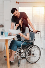 A woman in a wheelchair after a car accident and working with a computer at home with her lover....