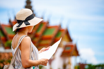 Asian woman holding brochure map guide for study history in Bangkok ,Thailand.