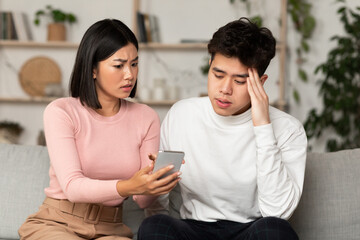 Chinese Girlfriend Showing Cheating Boyfriend His Cellphone Sitting At Home