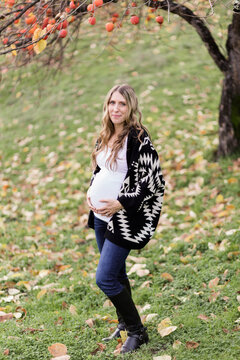 Happy young pregnant woman under a persimmon tree