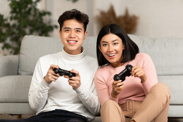 Joyful Asian Boyfriend And Girlfriend Playing Video Game At Home © Prostock-studio