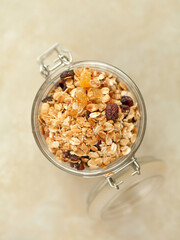 Homemade muesli in a glass jar on a beige textured background