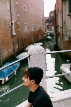 Guy sitting on a bridge in Venice, Italy