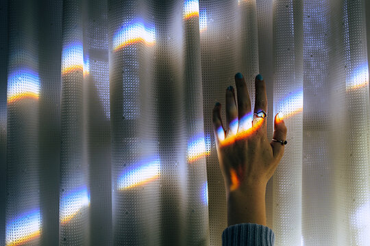 Female hand reaching up toward a prism of light