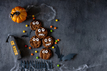 Modern Halloween background. Halloween cookies. Funny monsters made of biscuits with chocolate on the table. Halloween party decoration. Trick or treat concept.