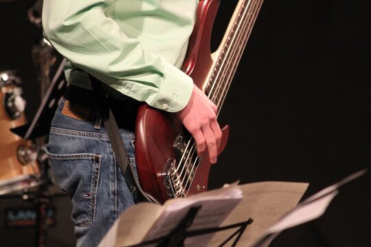 Nahaufnahme einer Bassgitarre mit 5 Seiten . Die Seiten werden vom Musiker angeschlagen. Elektrischer Bass in einer Bigband . Bassist beim Musizieren . Basssolo in Jazz Music . Base Detail Nahaufnahme