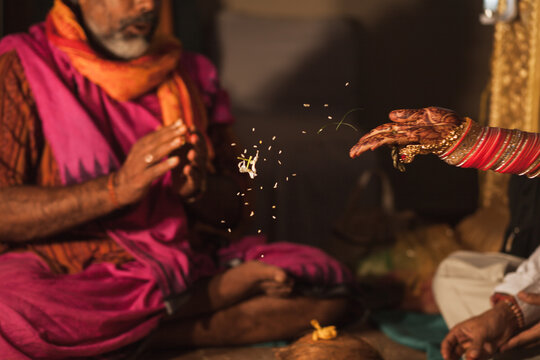 Bride's hand throwing flower petals in a fire during hindu wedding ceremony