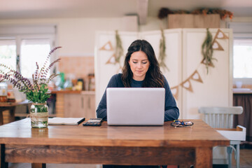 Brunette woman working with the laptop in her eco farm.