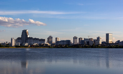 Fototapeta na wymiar Panorama of the skyline of Minsk through Lake Drozdy in the daytime. Water smoothness with reflection