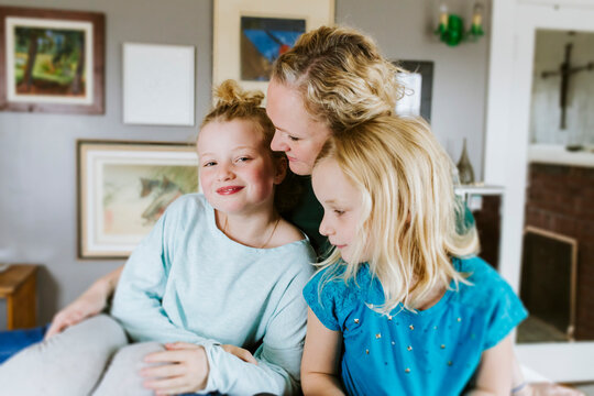 Mother and daughters cuddling together at home