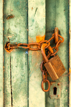 Old green rural door with rusty padlock