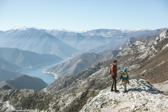 young boy sitting on top of a mountain overlooking macedonian mountain landscape