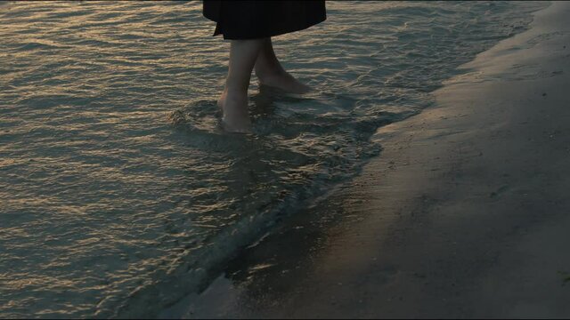 Girl walking along the baltic sea. Waves are crashing against her legs and feet.