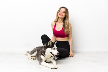 Young sport girl with her dog sitting on the floor looking up while smiling