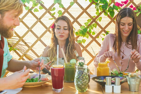 Jealous woman looking at boyfriend flirting with her friend other in pub. Love concept.