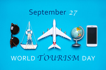 Happy world tourism day. Touristic objects, smart phone, sunglasses, globe and decorative airplane and vessel on blue background. Flat lay, top view. Text September 27, WORLD TOURISM DAY