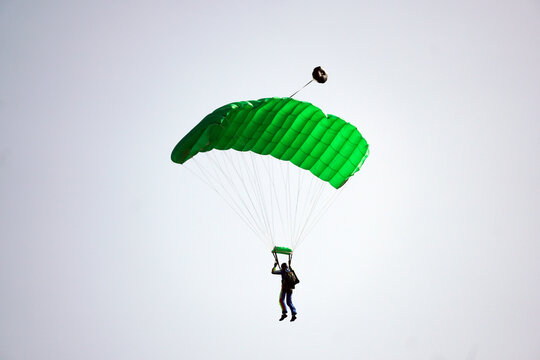 Parachutist jamped from an airplane uses a parachute to land.