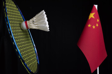Shuttlecock, badminton racket, and the flag China or Five-starred Red Flag on dark background. Concept of badminton tournament between countries.