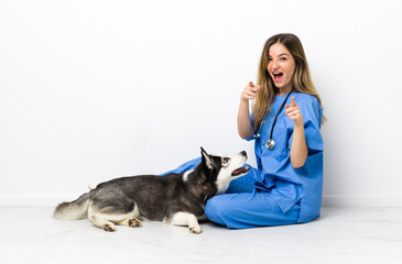 Veterinary doctor with Siberian Husky dog sitting on the floor points finger at you