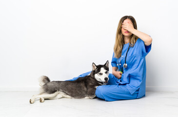 Veterinary doctor with Siberian Husky dog sitting on the floor covering eyes by hands