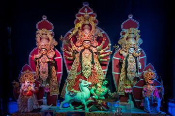 Decorated Durga Puja pandal with Goddess Durga family idol, Durga Puja festival at night. Shot under colored light at Howrah, West Bengal, India.