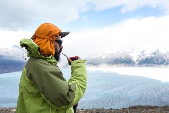 Hiker drinking mate, South American tea like drink and overlooking ice field in Torres Del Paine National Park in Chilean Patagonia