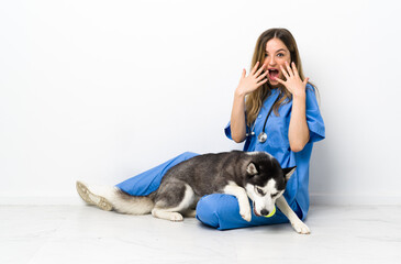 Naklejka na ściany i meble Veterinary doctor with Siberian Husky dog sitting on the floor with surprise facial expression