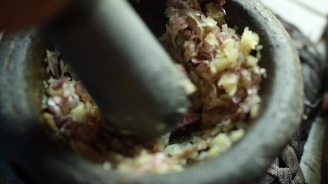 Thai chef using mortar crush an garlic mix with chili and herbs to making a spicy sauce. Culinary and eating thai Street food concept. 