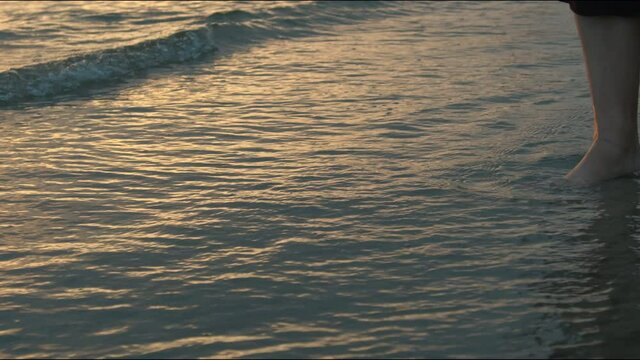 Girl walking along the baltic sea. Waves are crashing against her legs and feet.