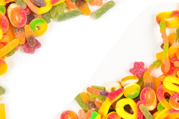 Frame of assorted gummy candies isolated on white. Top view. Space for text or design.