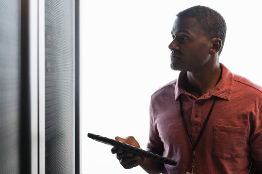Close up of backlit black technician looking up at a bank of ser