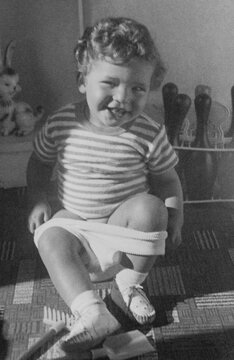 Scanned vintage photo of small child sitting on a potty