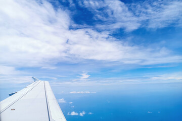 Airplane flight. Wing of an airplane flying above the golden fluffy clouds moving softly on the sky and the sun shining through the clouds with beautiful rays.