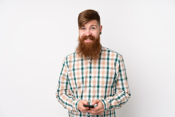 Redhead man with long beard over isolated white background sending a message with the mobile