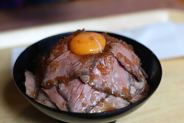 Close up of a bowl of delicious barbecue  beef rice with raw egg yolk topping