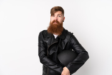 Redhead man with long beard holding a motorcycle helmet over isolated white background keeping arms crossed