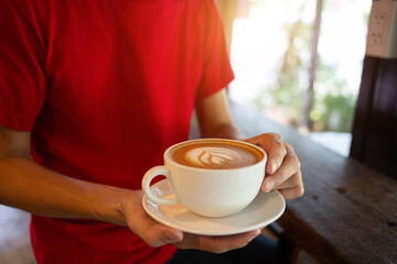 Hand put a Latte arts coffe hot coffee on wooden table.barista love art concept.