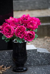 closeup of pink artificial flowers on tomb in a cemetery